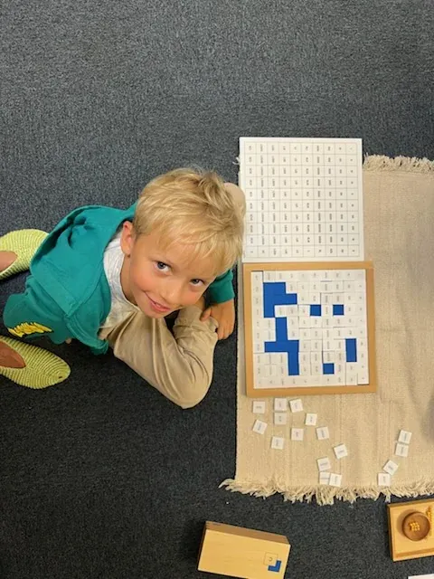Chłopiec przy pracy z materiałem Montessori — tablicą z niebiesko-białych płytek
